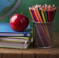 book with an apple on top and pencils on the side