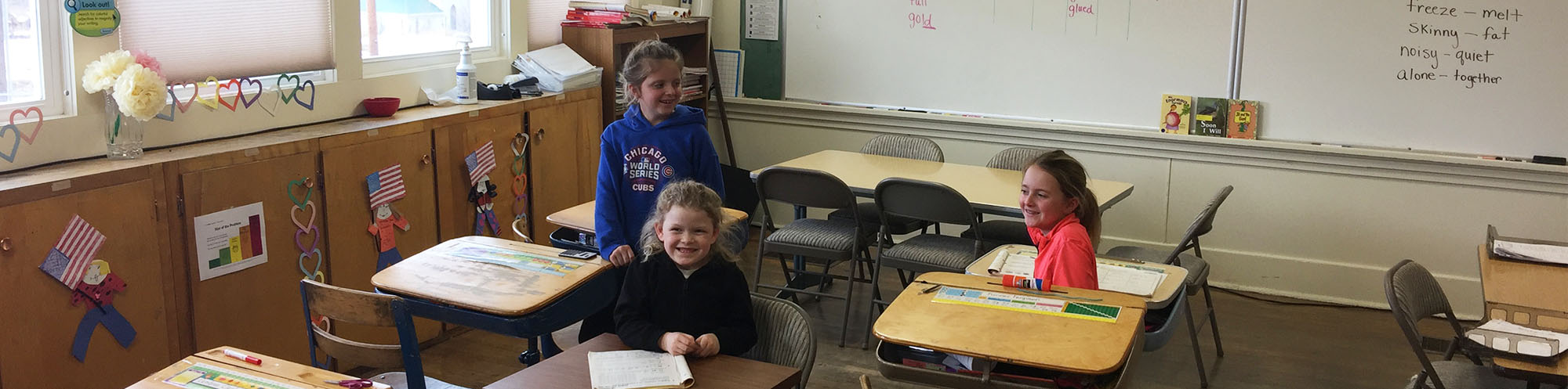 Three happy elementary school girls sitting in a classroom